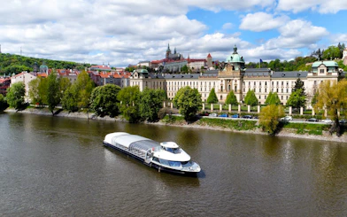 River cruise boat on Vltava River with Prague Castle in the background.