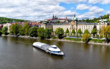 River cruise boat on Vltava River with Prague Castle in the background.
