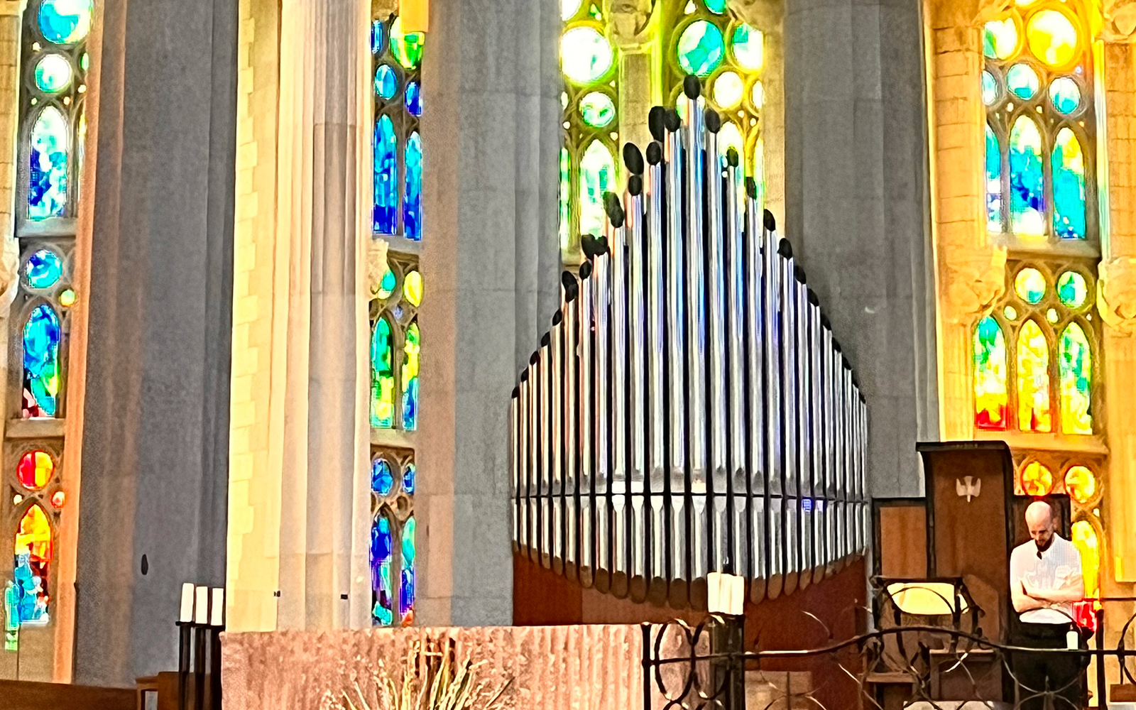 Organ pipes inside Sagrada Familia, Barcelona with colorful stained glass windows.