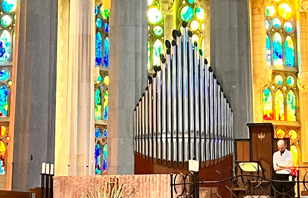 Organ pipes inside Sagrada Familia, Barcelona with colorful stained glass windows.