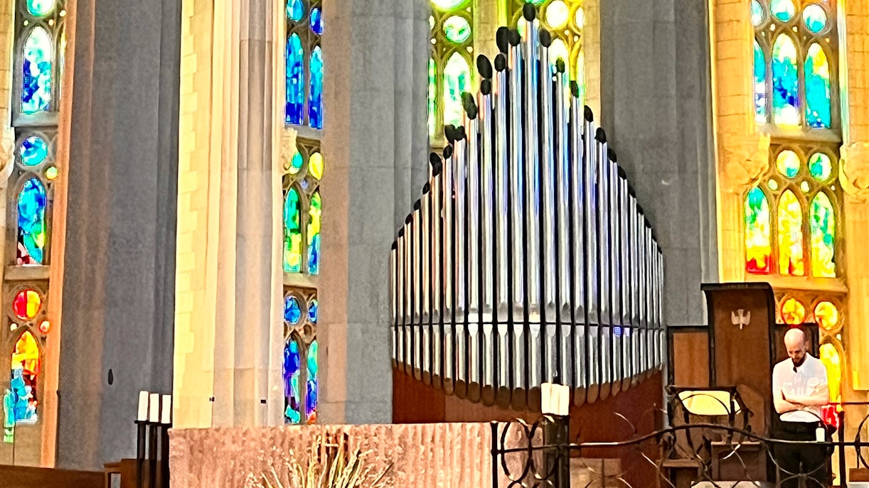 Organ pipes inside Sagrada Familia, Barcelona with colorful stained glass windows.