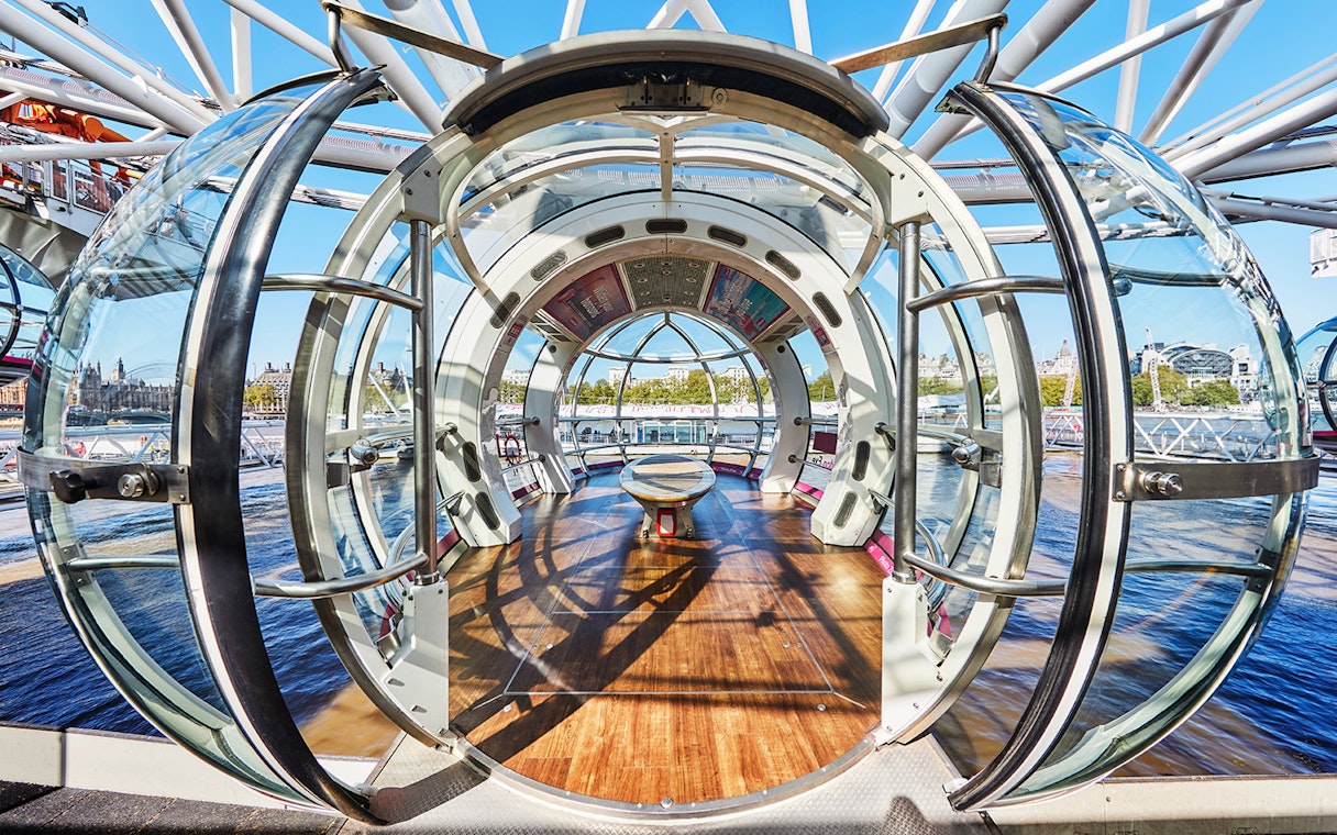 Interior view of a London Eye pod with cityscape in the background.