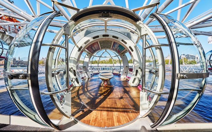 Interior view of a London Eye pod with cityscape in the background.