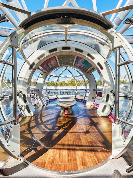 Interior view of a London Eye pod with cityscape in the background.