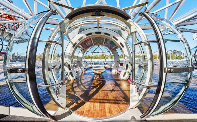 Interior view of a London Eye pod with cityscape in the background.