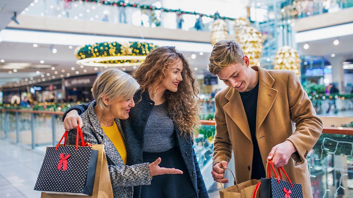 Family shopping in a Swiss mall with holiday decorations and various stores in the background.