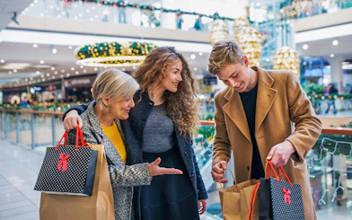 Family shopping in a Swiss mall with holiday decorations and various stores in the background.