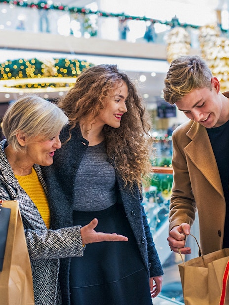Family shopping in a Swiss mall with holiday decorations and various stores in the background.