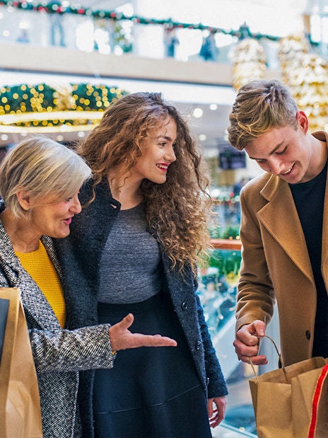 Family shopping in a Swiss mall with holiday decorations and various stores in the background.