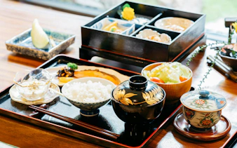 Traditional Japanese meal with rice, miso soup, and assorted dishes in a bento box.