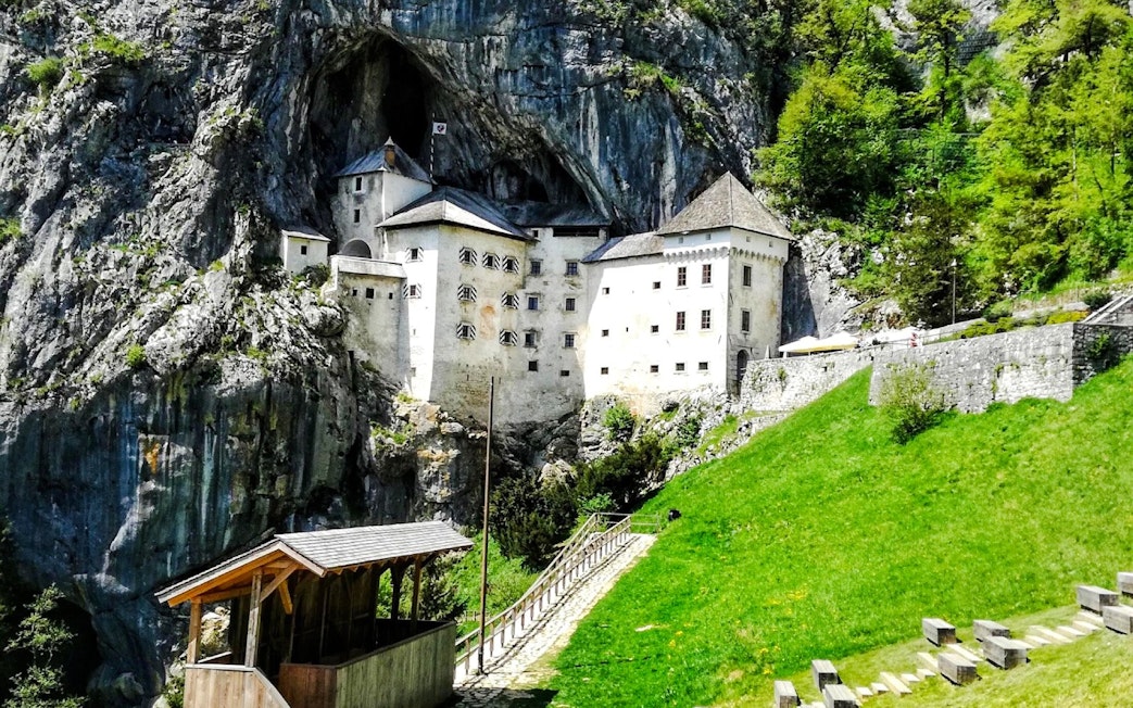 Predjama Castle nestled in a cliffside with surrounding greenery in Slovenia.