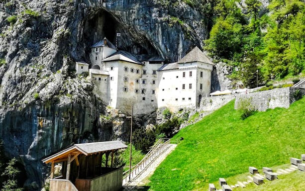 Predjama Castle nestled in a cliffside with surrounding greenery in Slovenia.