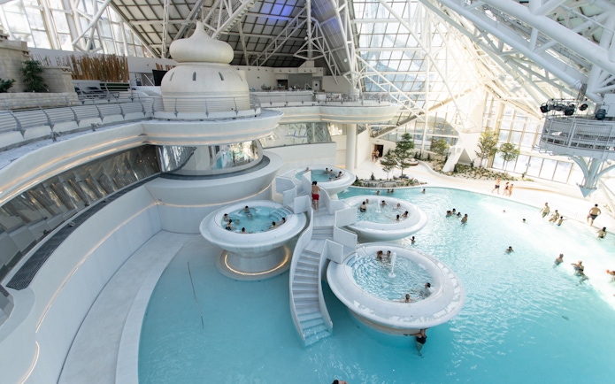 Indoor pools and hot tubs at Caldea spa resort, Andorra, with visitors enjoying the water.