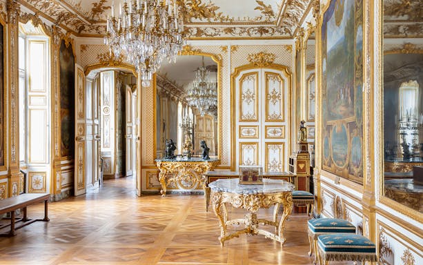 Chateau of Chantilly ornate room with gilded decor and chandeliers.