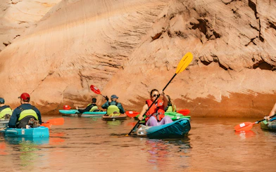 Kayakers paddling on Lake Powell near Antelope Canyon's sandstone walls.