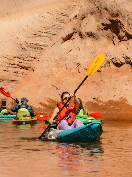 Kayakers paddling on Lake Powell near Antelope Canyon's sandstone walls.