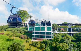 Singapore Cable Car passing Mount Faber Peak station amidst lush greenery.