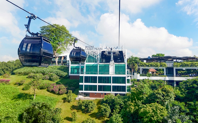 Singapore Cable Car passing Mount Faber Peak station amidst lush greenery.