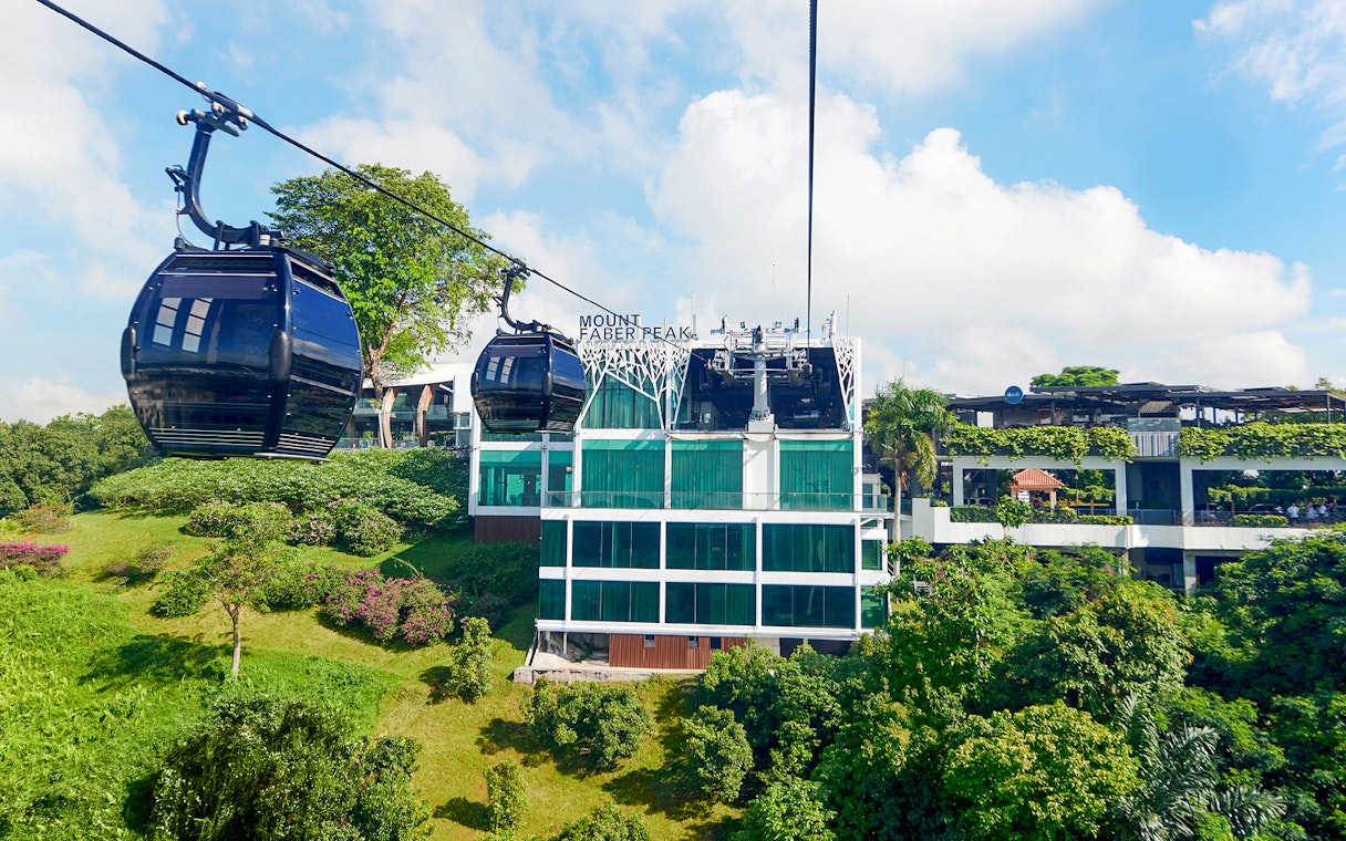 Singapore Cable Car passing Mount Faber Peak station amidst lush greenery.