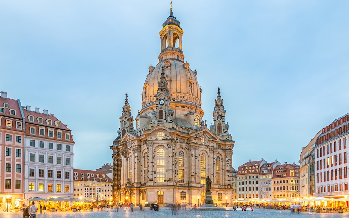 Frauenkirche in Dresden with illuminated dome and surrounding square at dusk.