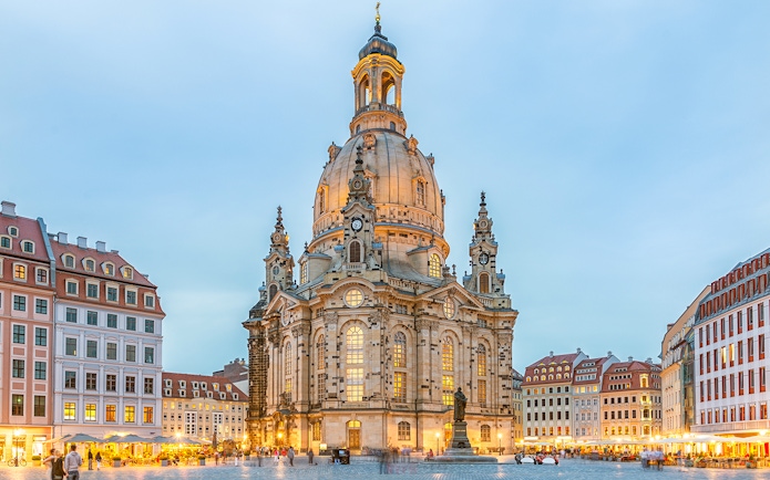 Frauenkirche in Dresden with illuminated dome and surrounding square at dusk.