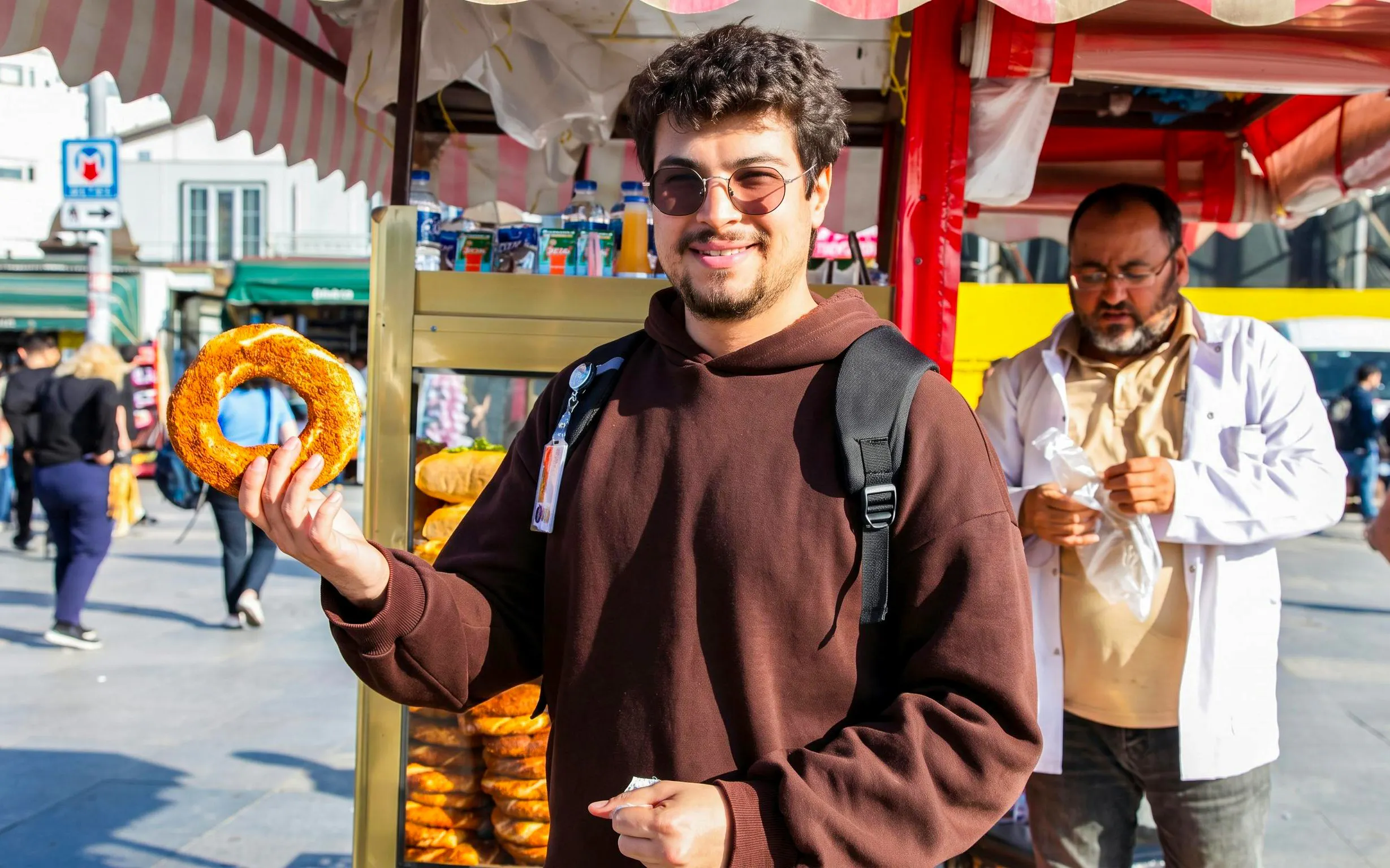 Man holding simit at a street food stall in Istanbul.
