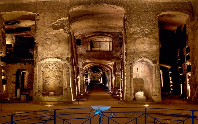 Catacombs of San Gennaro, ancient underground burial site with illuminated arches and passageways.