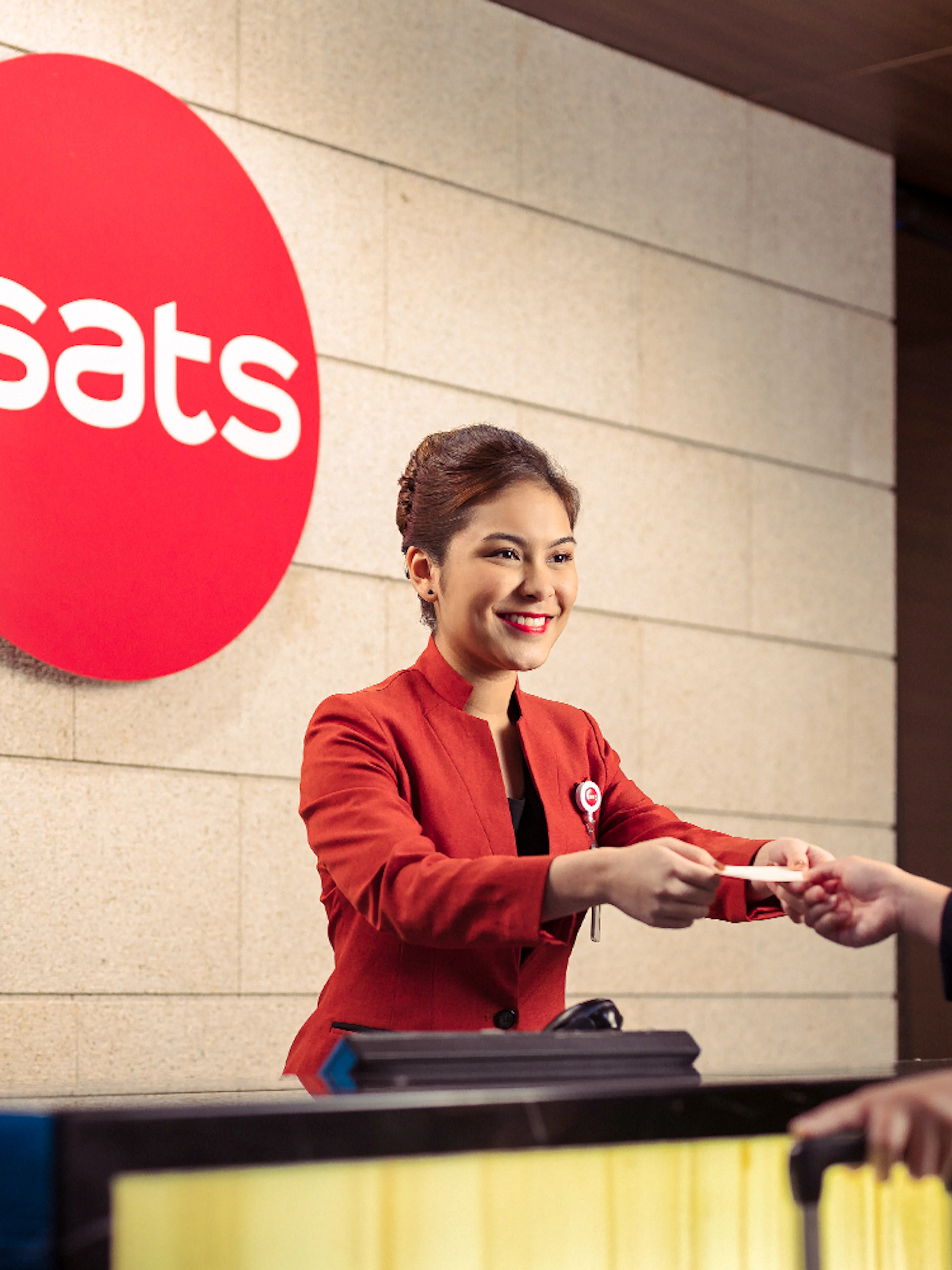 SATS staff assisting a guest at Plaza Premium Lounge reception, Singapore.