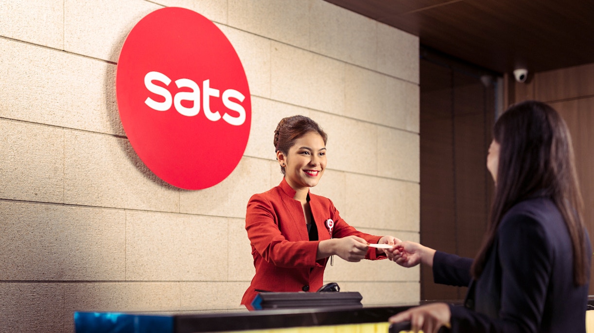 SATS staff assisting a guest at Plaza Premium Lounge reception, Singapore.