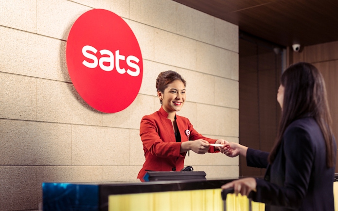 SATS staff assisting a guest at Plaza Premium Lounge reception, Singapore.