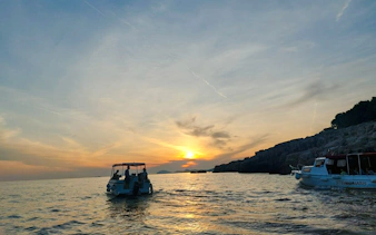 Boat tour at sunset near Dubrovnik coastline, part of History Walk & Dubrovnik Panorama by Boat.