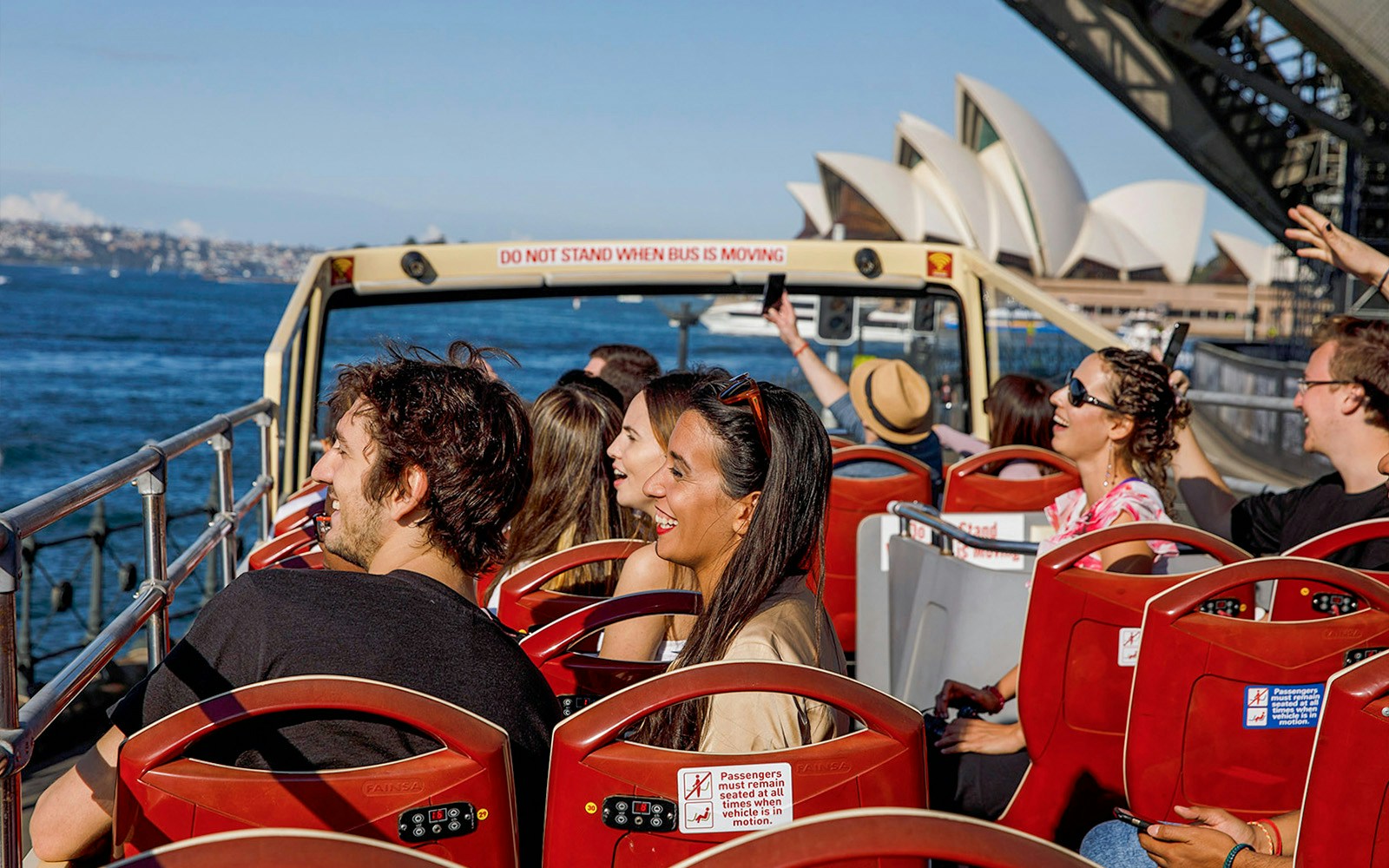 Big Bus Sydney tour near Sydney Opera House with passengers enjoying the ride.