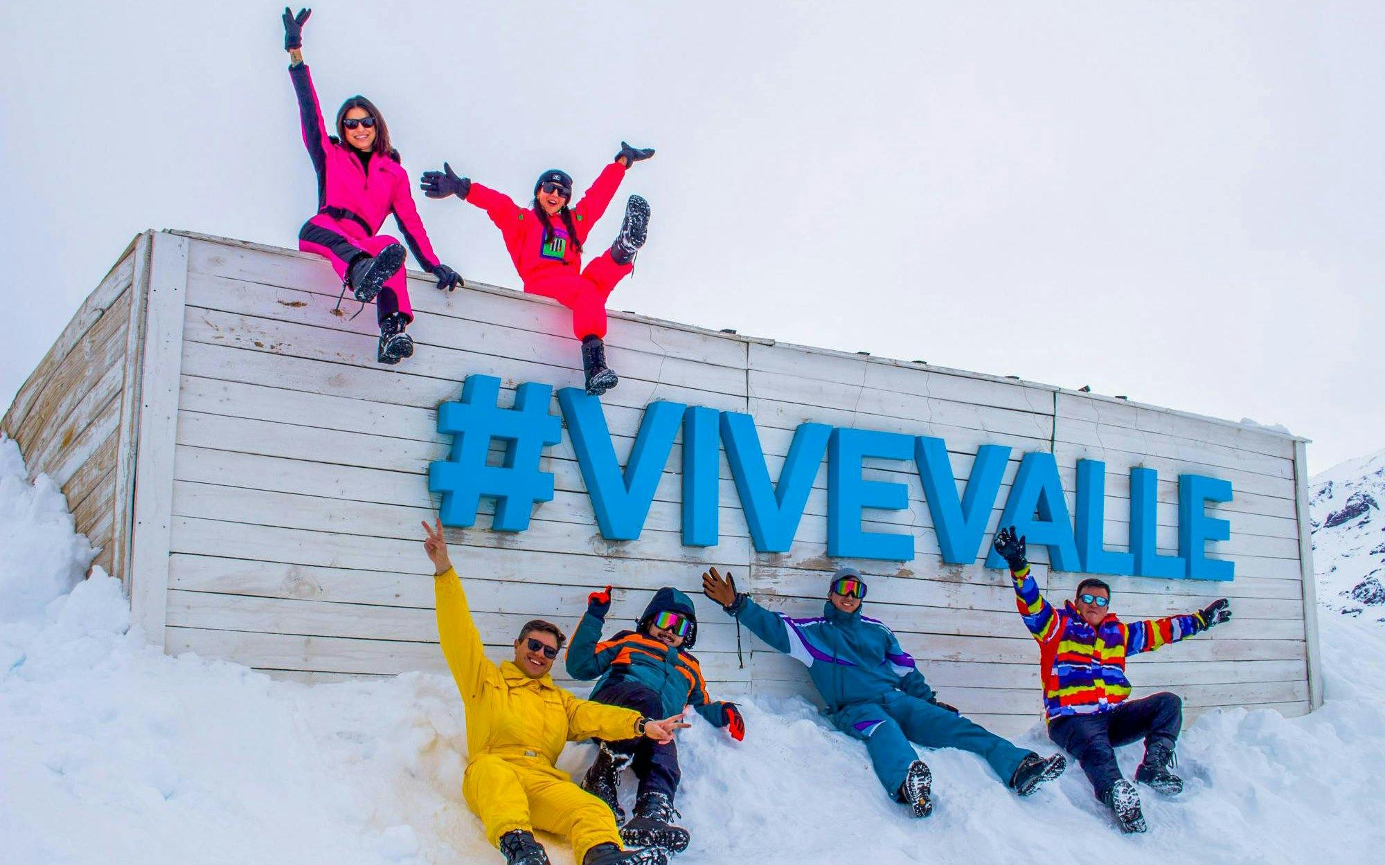 Group enjoying snow at Valle Nevado ski resort, Chile, with #ViveValle sign.