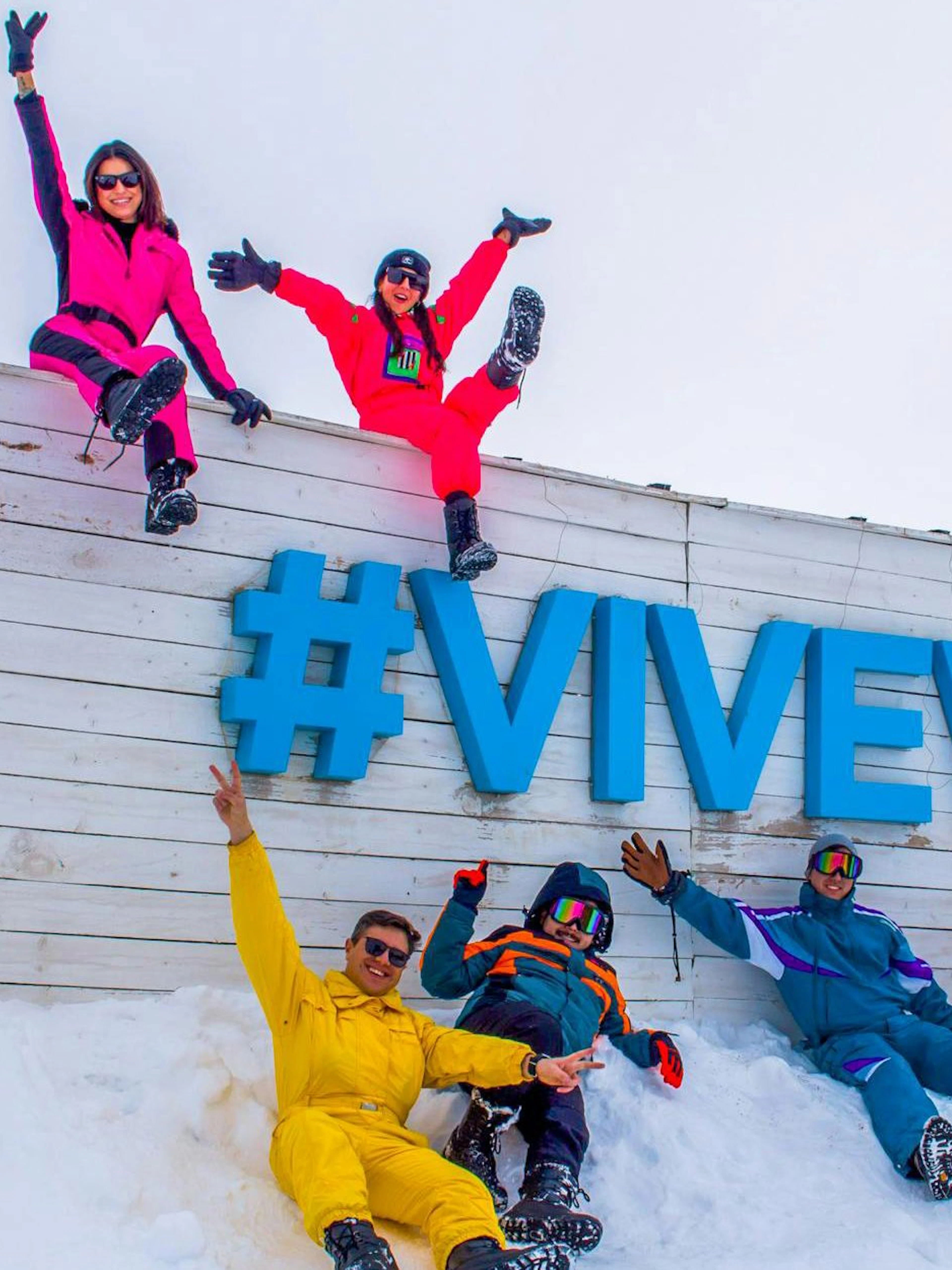 Group enjoying snow at Valle Nevado ski resort, Chile, with #ViveValle sign.
