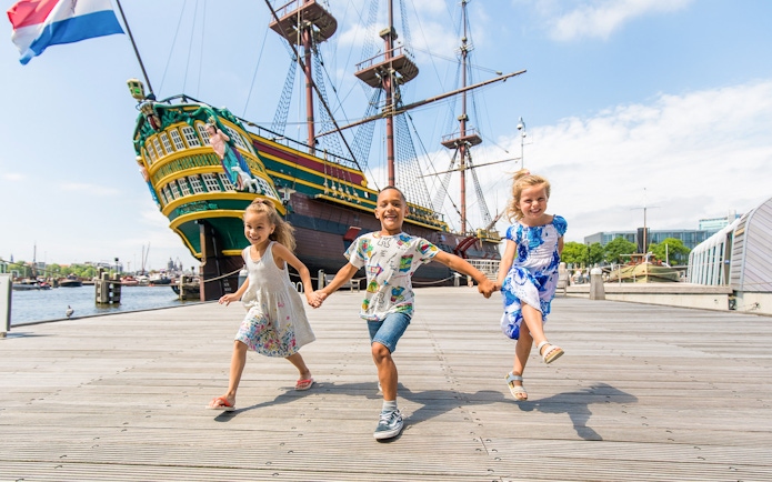 Children playing outside the National Maritime Museum with a historic ship in the background.