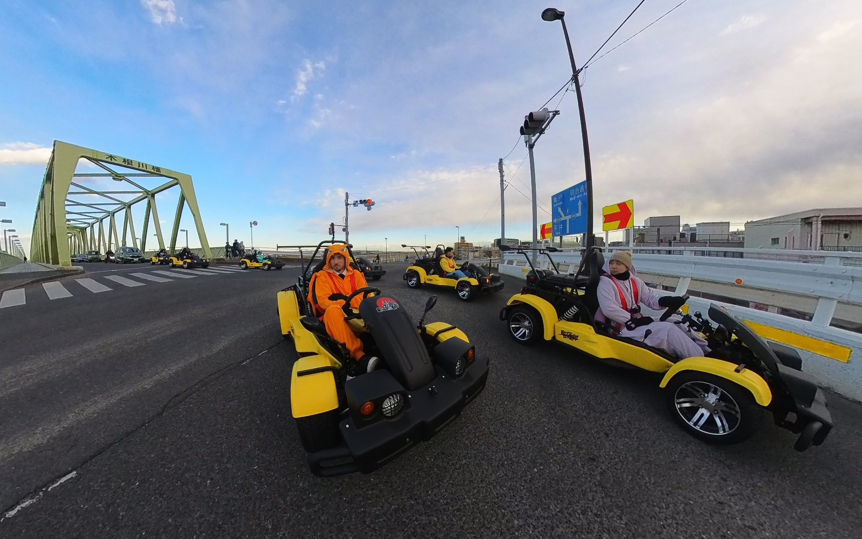Go-kart tour crossing a bridge in Tokyo's old town, featuring participants in costumes.