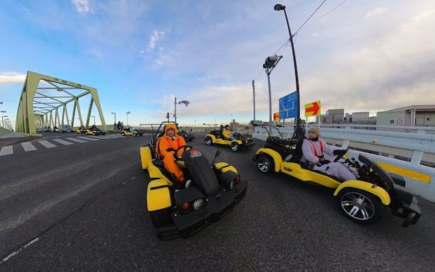 Go-kart tour crossing a bridge in Tokyo's old town, featuring participants in costumes.