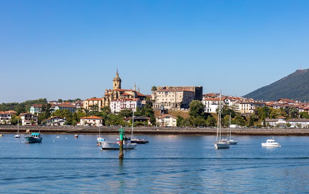 Hondarribia waterfront with boats and historic buildings under a clear blue sky.