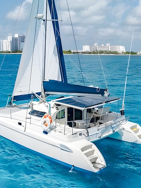 Catamaran sailing near Isla Mujeres with city skyline in the background.