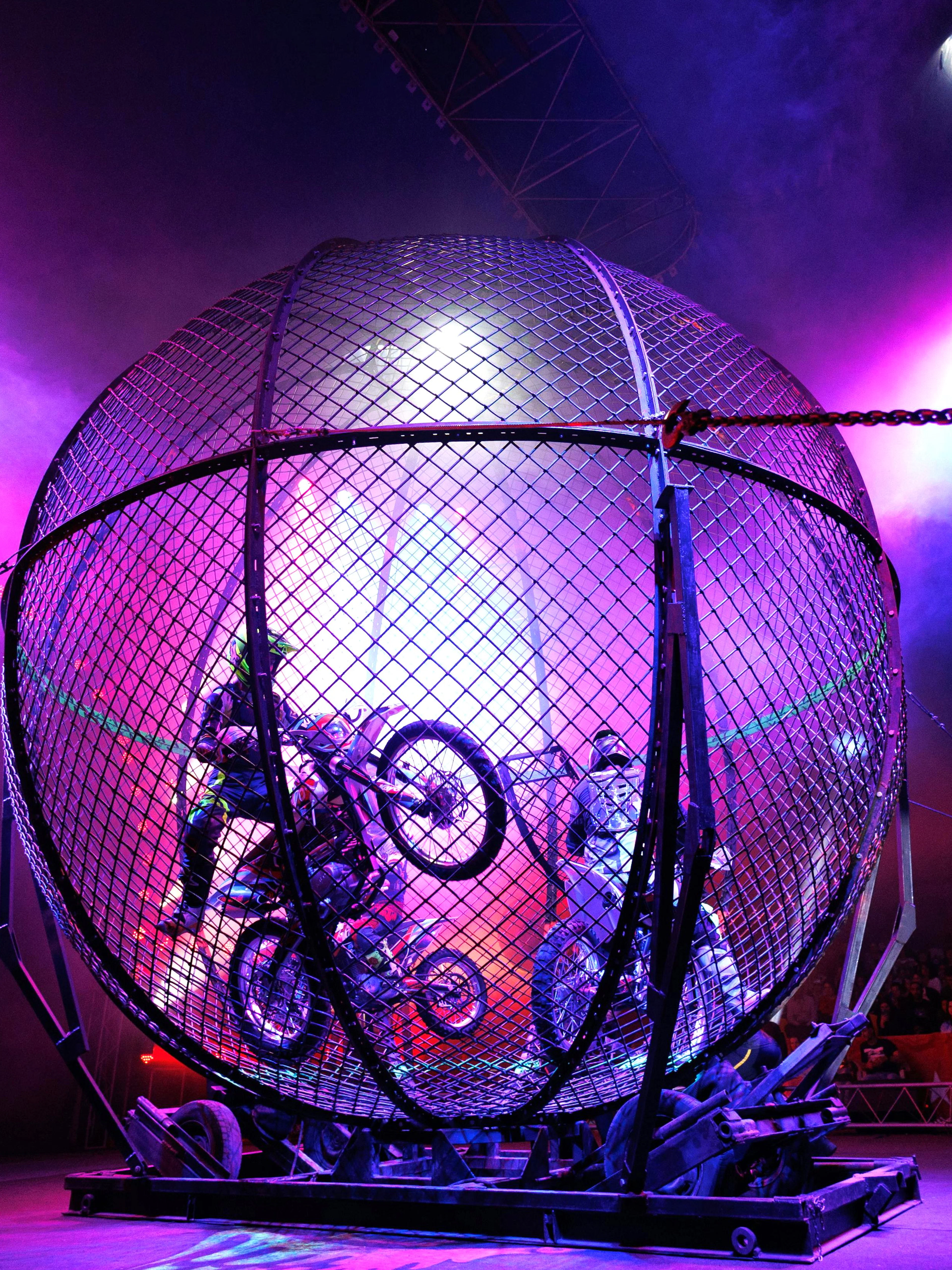 Motorcycle stunt riders perform loops inside the Globe of Death at Phuket Circus show.