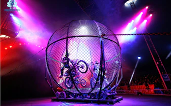 Motorcycle stunt riders perform loops inside the Globe of Death at Phuket Circus show.