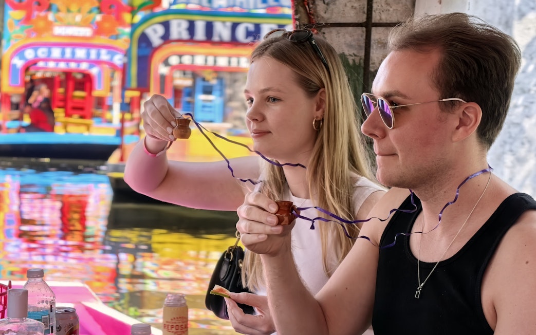 Couple enjoying drinks on a colorful boat in Xochimilco, Mexico City.