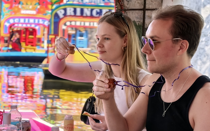 Couple enjoying drinks on a colorful boat in Xochimilco, Mexico City.