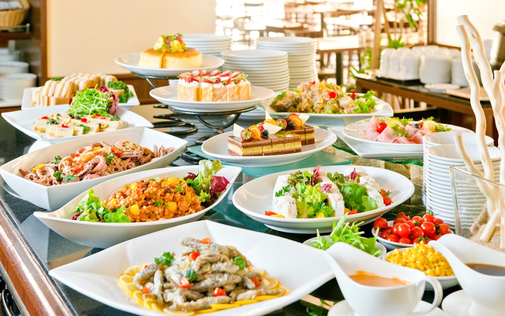 Buffet spread with various dishes at a lunch event in a scenic outdoor setting.