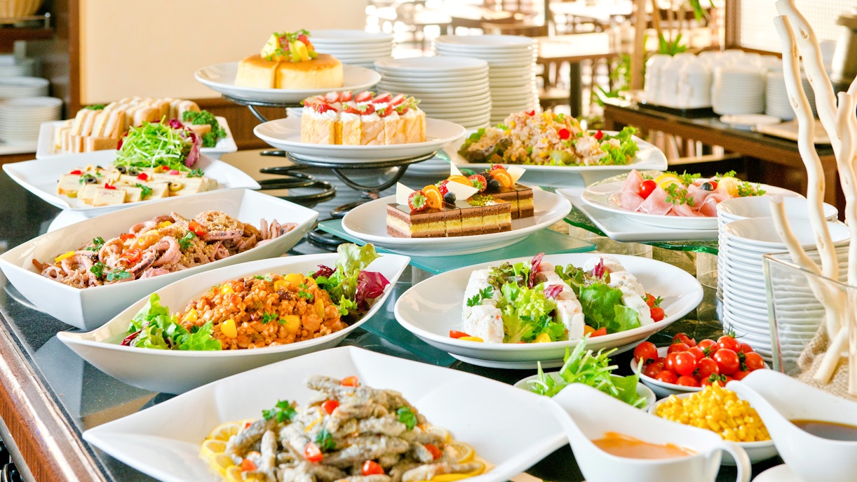Buffet spread with various dishes at a lunch event in a scenic outdoor setting.