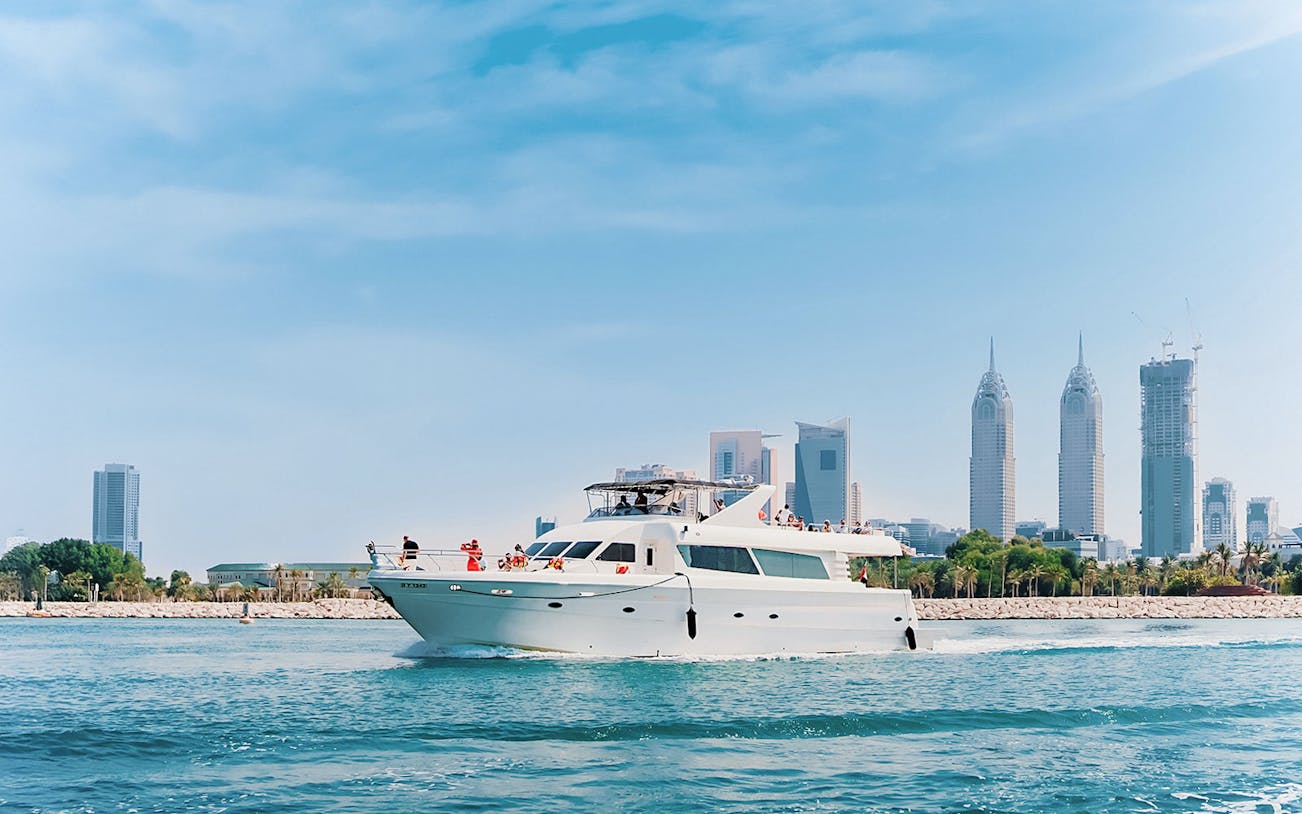 Luxury yacht cruising near Dubai Harbour with city skyline in the background.
