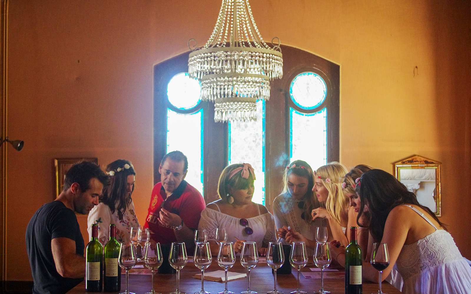Wine tasting session in Saint-Emilion with a group of people under a chandelier.