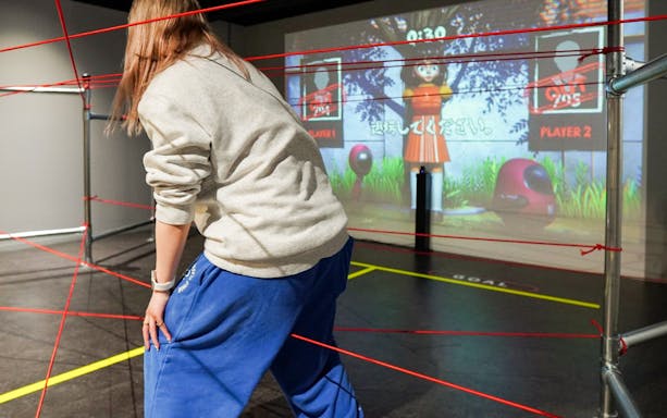 Participant navigating a laser maze at RED TOKYO TOWER interactive game area.