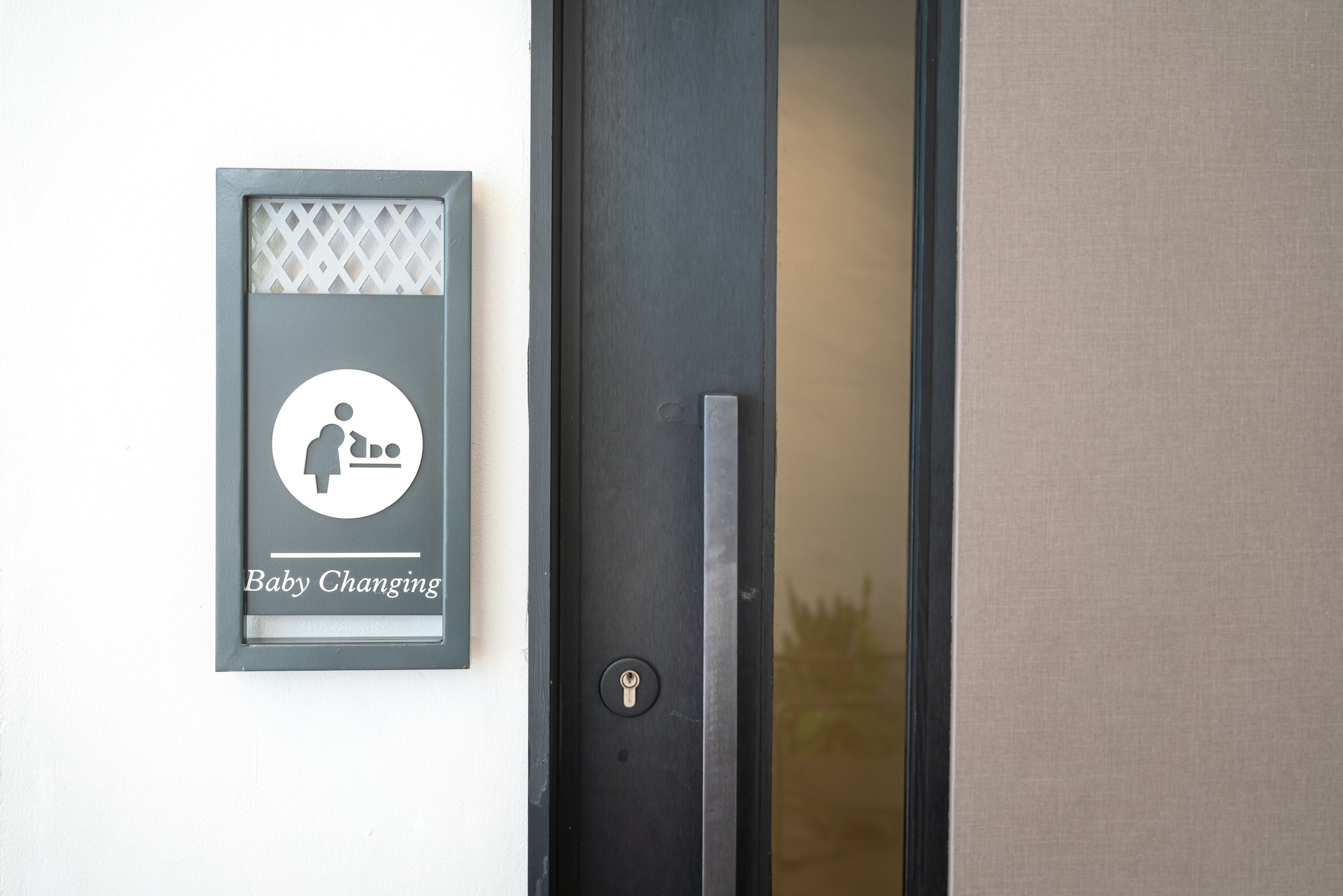 Baby changing station sign next to a door.