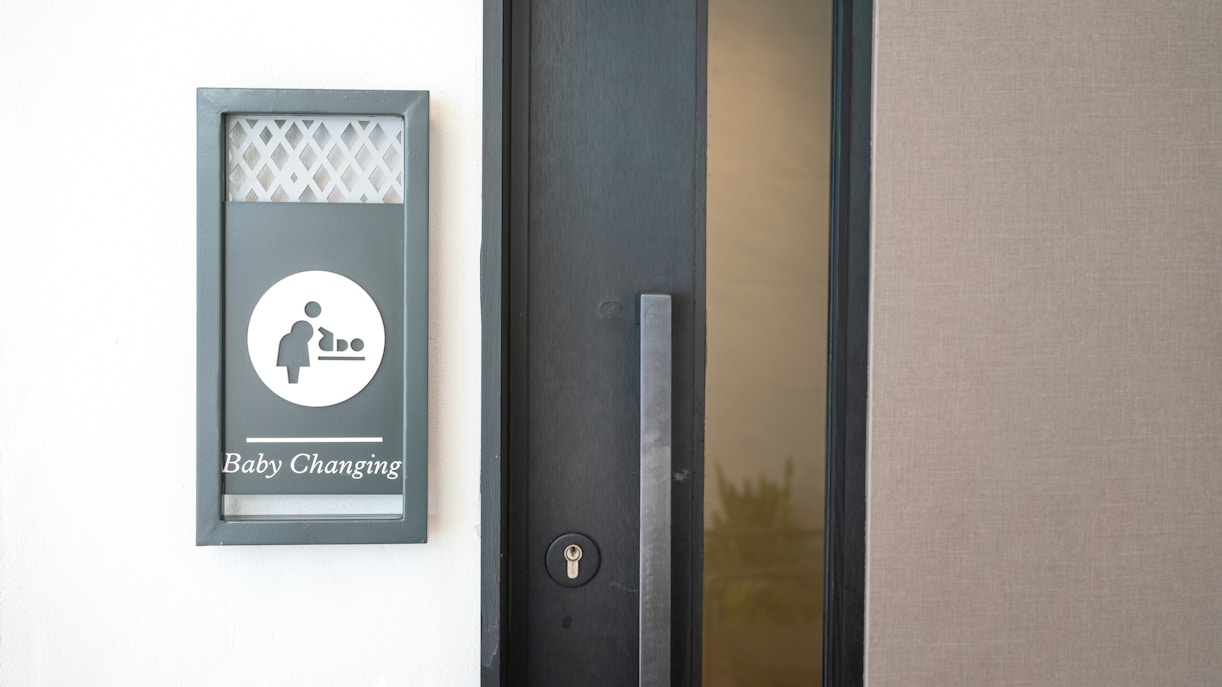 Baby changing station sign next to a door.